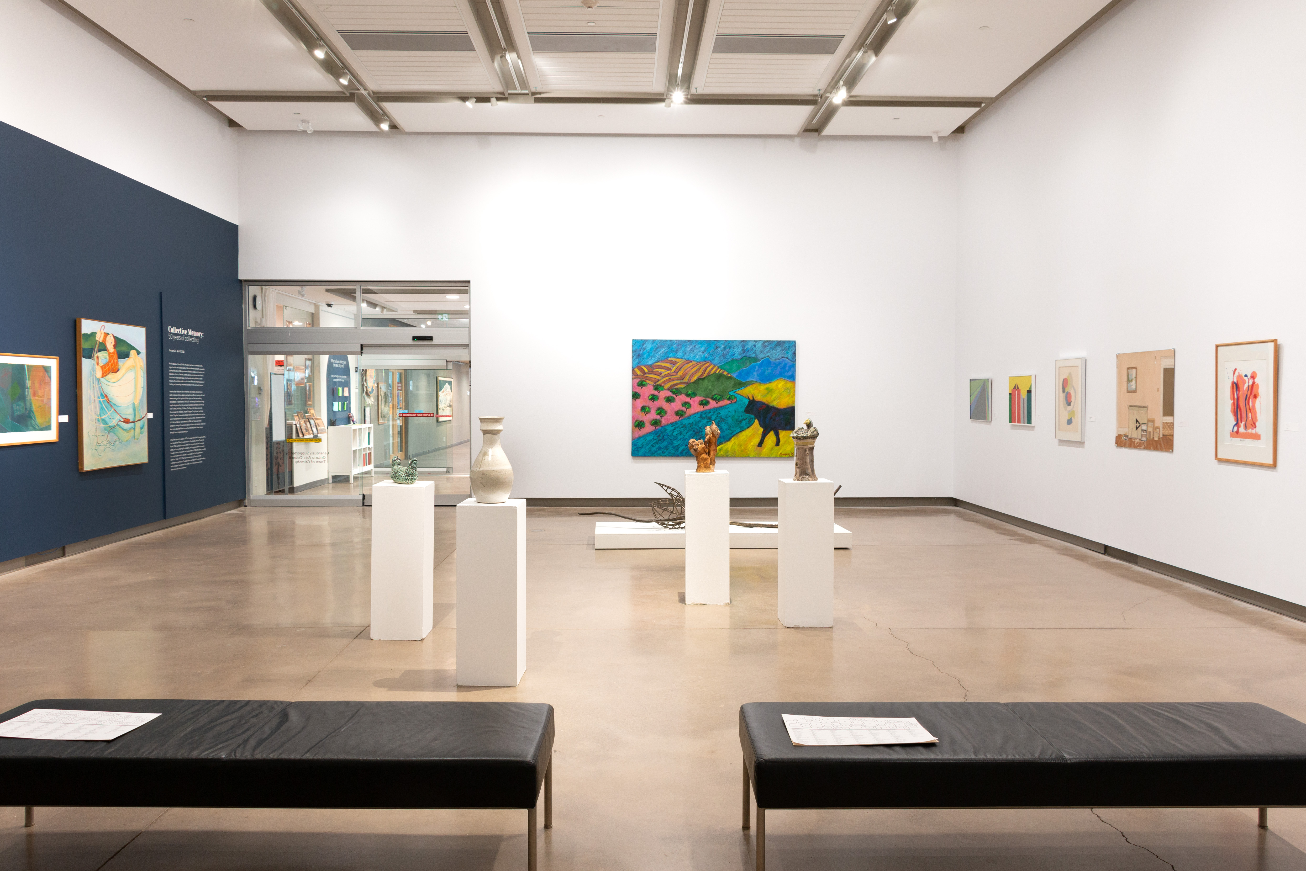 an exhibition overview of the gallery space, with paintings on the wall and sculptures on plinths in the middle of the room